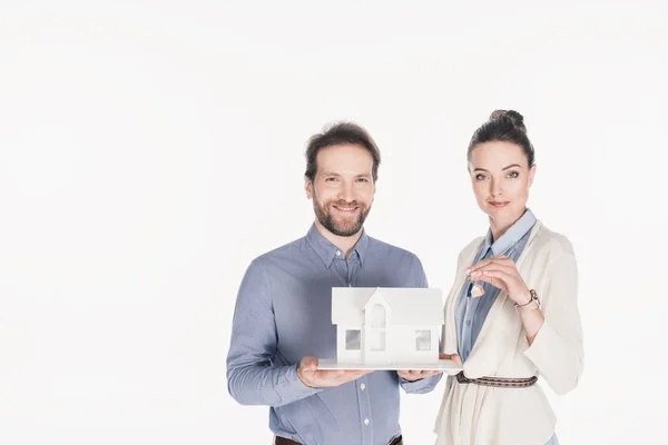 Retrato de casal sorridente com modelo de casa e chave isolada em branco — Fotografia de Stock