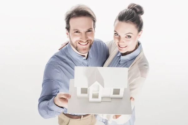 Visão de alto ângulo de casal sorridente segurando modelo de casa em conjunto isolado no branco — Fotografia de Stock
