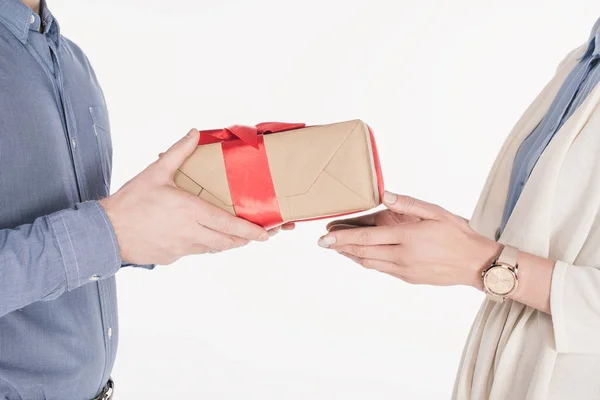 Side view of man presenting wrapped gift to woman isolated on white — Stock Photo