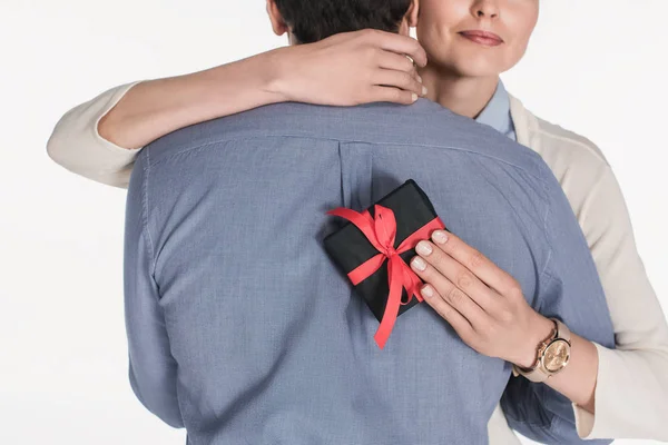 Vista parcial de la mujer con regalo envuelto en la mano abrazo marido aislado en blanco - foto de stock