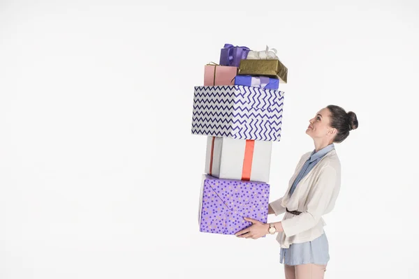 Vista lateral de mujer sosteniendo pila de regalos envueltos aislados en blanco - foto de stock