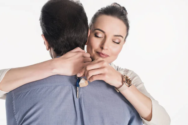 Partial view of woman with key from new house hugging husband isolated on white — Stock Photo