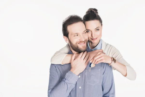 Ritratto di donna con chiave da nuova casa abbracciando sorridente marito isolato su bianco — Foto stock