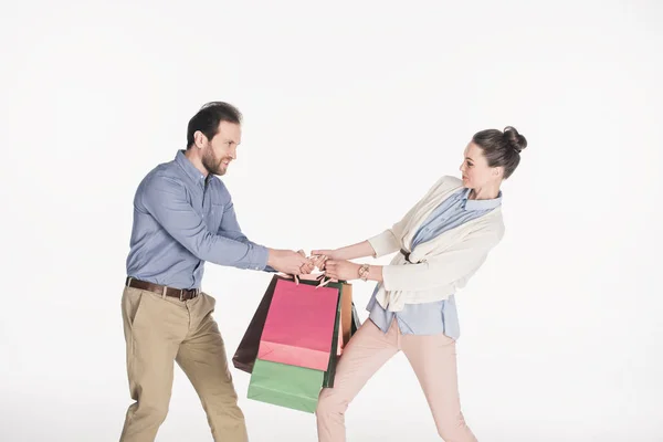 Vista lateral de la pareja deteniendo bolsas de compras aisladas en blanco - foto de stock