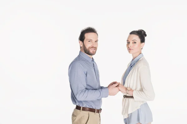 Vue latérale du couple marié tenant la main et regardant la caméra ensemble isolé sur blanc — Photo de stock