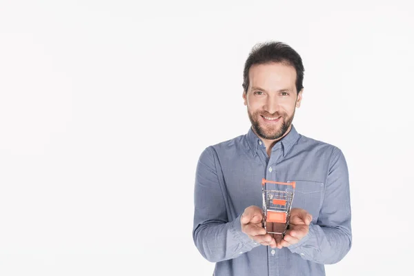 Ritratto di uomo barbuto sorridente con piccolo carrello della spesa in mani isolate su bianco — Foto stock