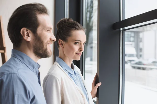 Side view of smiling couple looking out window together — Stock Photo