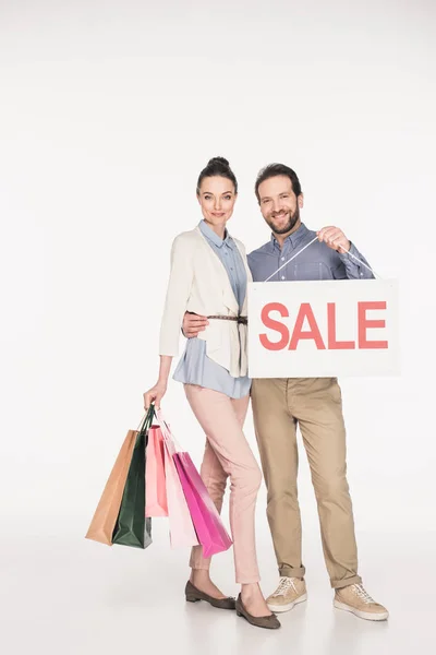 Coppia sorridente con banner in vendita e shopping bag isolate su bianco — Foto stock