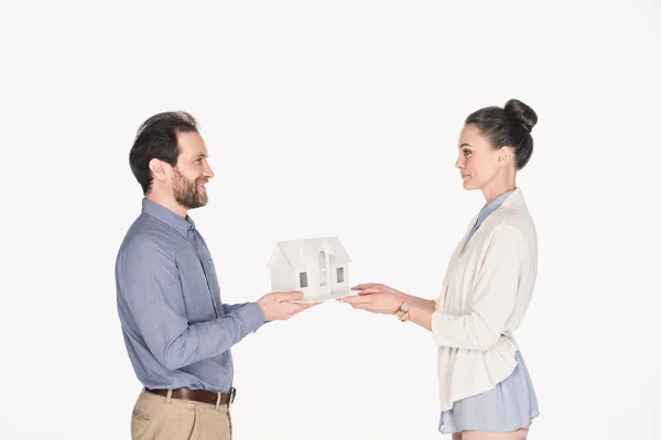 Vue latérale du couple tenant modèle de maison dans les mains ensemble isolé sur blanc — Photo de stock