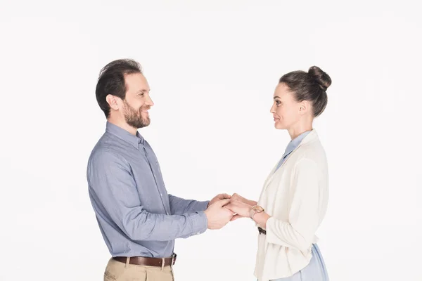 Vista lateral de la esposa sonriente y el marido tomados de la mano juntos aislados en blanco - foto de stock