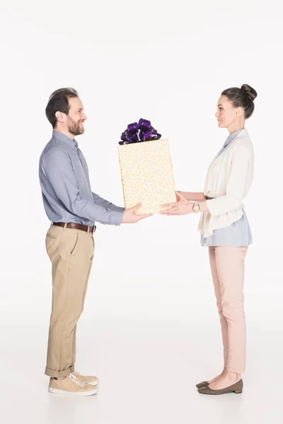 Side view of smiling man presenting wrapped gift to wife isolated on white — Stock Photo
