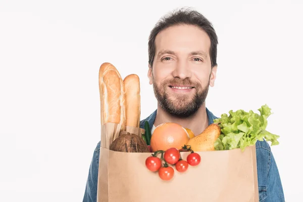 Усміхнений бородатий чоловік з паперовим пакетом, повним їжі, ізольований на білому — стокове фото