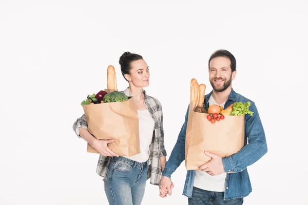 Married couple holding hands together while carrying paper packages with food isolated on white — Stock Photo