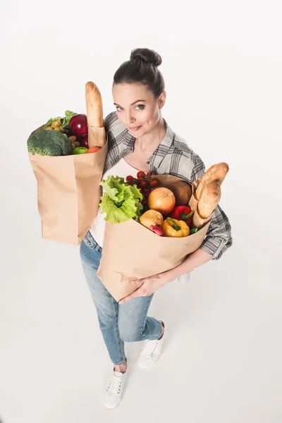 Hochwinkel-Ansicht der attraktiven Frau hält Papierpakete mit Lebensmittelgeschäft isoliert auf weiß — Stockfoto