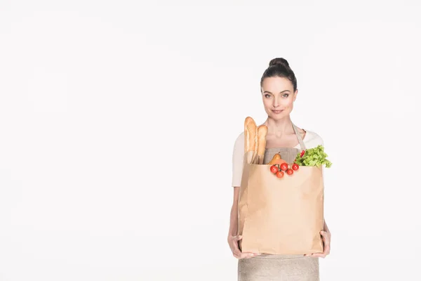 Portrait of woman in apron holding paper package full of food isolated on white — Stock Photo