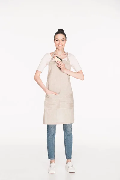 Smiling woman in apron showing credit card in hand isolated on white — Stock Photo