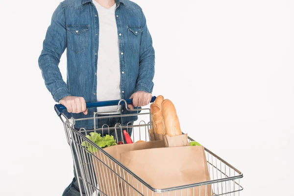 Visão parcial do homem com carrinho de compras cheio de embalagens de papel com alimentos isolados em branco — Fotografia de Stock