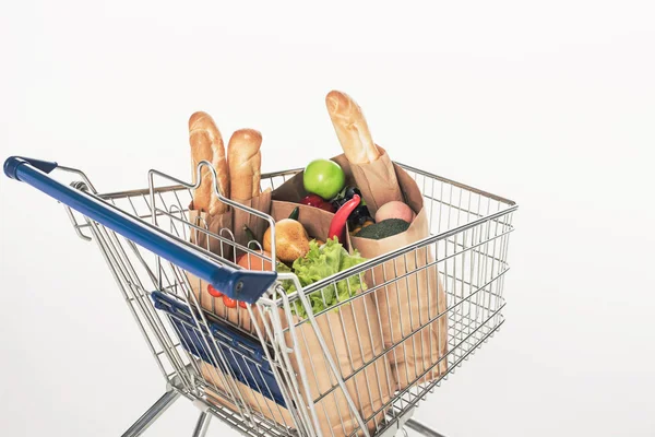 Vista da vicino del carrello della spesa con pacchi di carta pieni di generi alimentari isolati su bianco — Foto stock