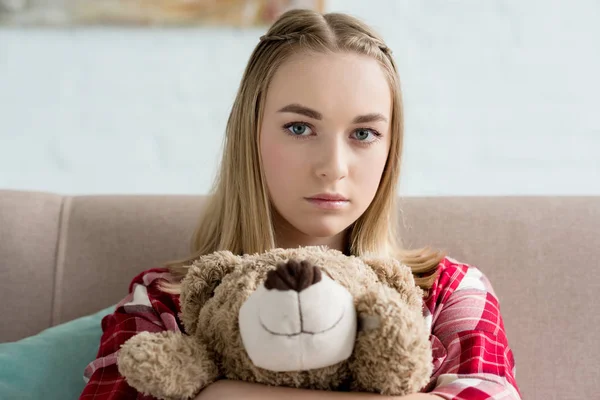 Primer plano retrato de hermosa adolescente abrazando su osito de peluche y mirando a la cámara - foto de stock