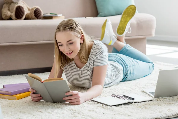Teen student girl reading book while lying on floor — Stock Photo