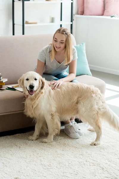Teen student girl petting her adorable golden retriever at home — Stock Photo