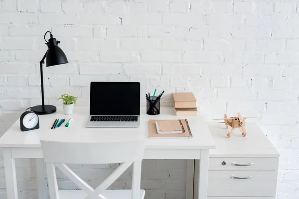 Work desk with laptop at home in front of white brick wall — Stock Photo