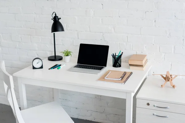 Lugar de trabajo moderno con el ordenador portátil en casa delante de la pared de ladrillo blanco - foto de stock