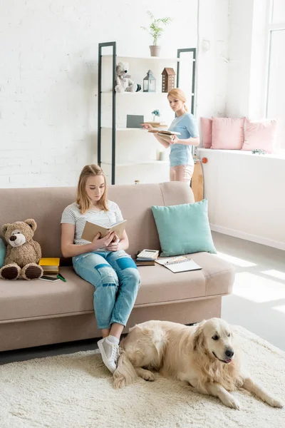 Mãe e filha adolescente lendo livros juntos em casa — Fotografia de Stock