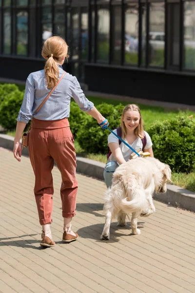 Mother and teen daughter spending time together on street with their dog — Stock Photo