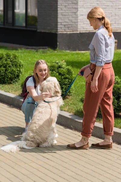 Мать и дочь проводят время вместе на улице со своей собакой — стоковое фото