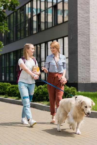 Mother and daughter walking on street with dog — Stock Photo