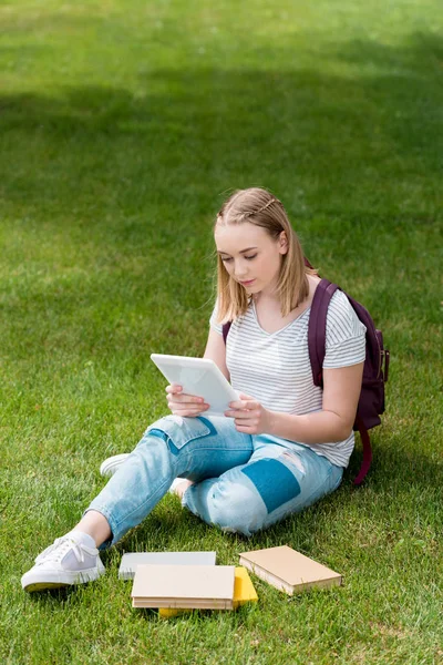 Підліток студент дівчина використовує планшет, сидячи на траві в саду — стокове фото