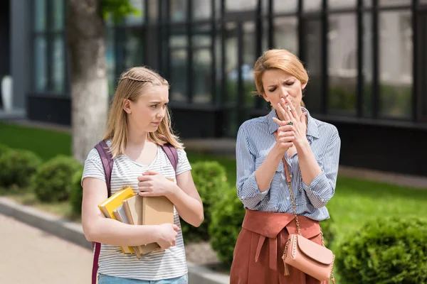 Disgustada hija adolescente mirando a la madre mientras fuma cigarrillo - foto de stock