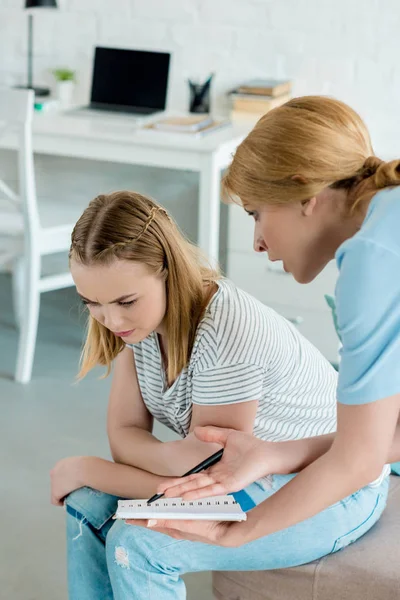 Angry mother showing notebook to daughter and yelling — Stock Photo