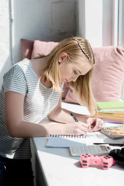 Vista laterale di focalizzato teen studente ragazza facendo i compiti — Foto stock
