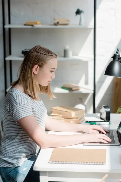 Vista lateral de adolescente estudiante chica trabajando con portátil en casa — Stock Photo