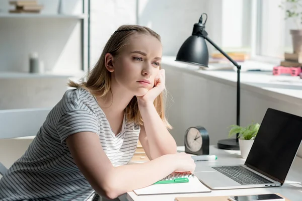 Reflexivo adolescente estudiante haciendo tarea y mirando hacia otro lado - foto de stock