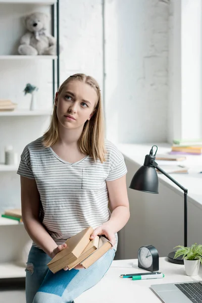 Thoughtful teen student girl with books sitting on work desk at home — Stock Photo