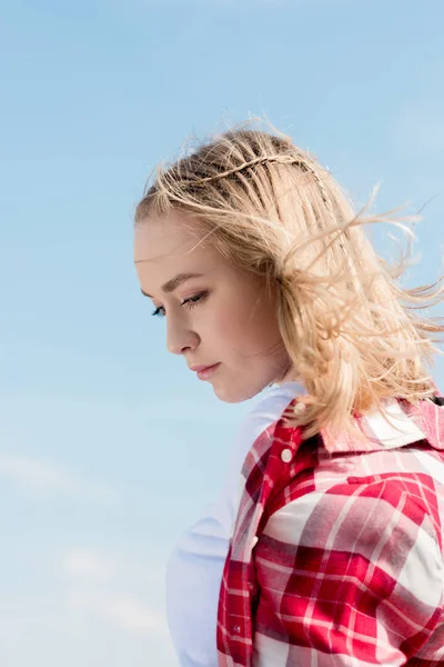 Thoughtful teen girl with hair waving on wind in front of blue sky — Stock Photo
