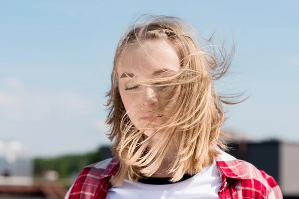 Beautiful teen girl with hair waving on wind in front of blue sky — Stock Photo