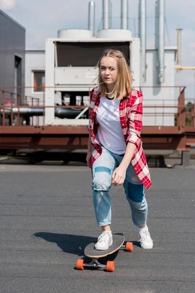 Active teen girl riding skateboard on rooftop — Stock Photo