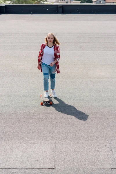 Vista ad alto angolo di adolescente ragazza in sella skateboard sul tetto — Foto stock