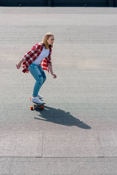 High angle view of active teen girl riding skateboard on rooftop — Stock Photo