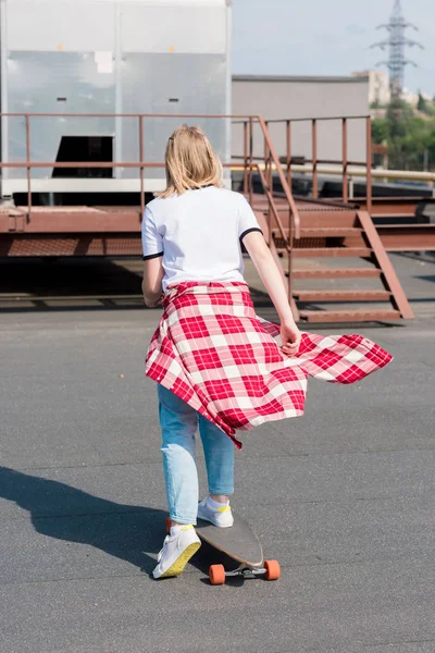Вид ззаду дівчини-підлітка, що їде скейтборд на даху — стокове фото