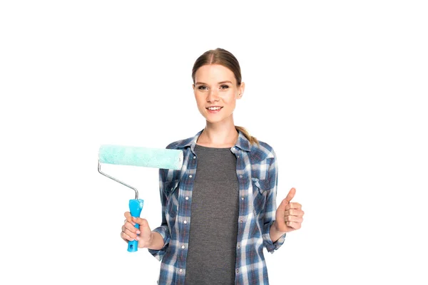 Smiling young woman doing thumb up gesture and holding paint roller isolated on white background — Stock Photo