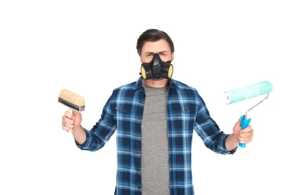 Mann in Atemschutzmaske hält Pinsel und Farbroller isoliert auf weißem Hintergrund — Stockfoto