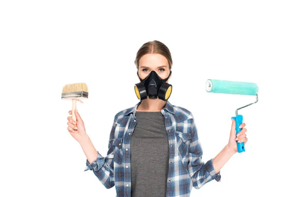Mujer en respirador sosteniendo pincel de pintura y rodillo de pintura aislado sobre fondo blanco — Stock Photo