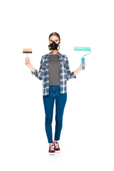 Giovane donna in respiratore tenendo pennello e rullo di vernice isolato su sfondo bianco — Foto stock