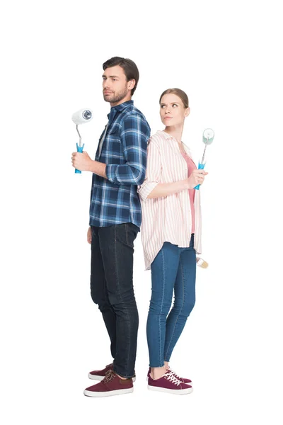 Couple avec rouleaux de peinture debout dos à dos isolé sur fond blanc — Photo de stock