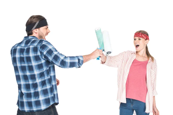 Young screaming man fighting with girlfriend by paint rollers isolated on white background — Stock Photo